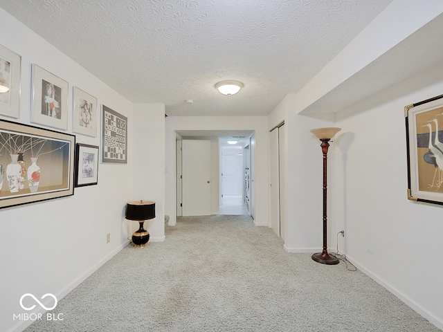 corridor with light colored carpet and a textured ceiling