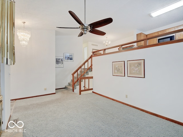 unfurnished living room featuring ceiling fan with notable chandelier and carpet flooring