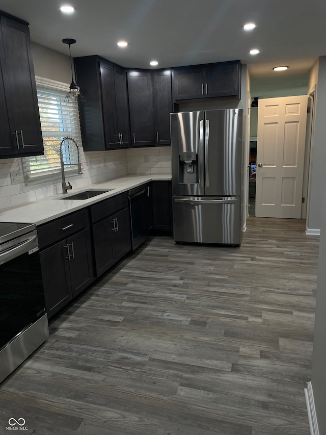 kitchen with appliances with stainless steel finishes, backsplash, dark hardwood / wood-style floors, hanging light fixtures, and sink