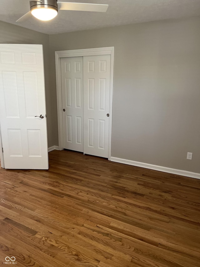 unfurnished bedroom with ceiling fan, a closet, and dark hardwood / wood-style floors