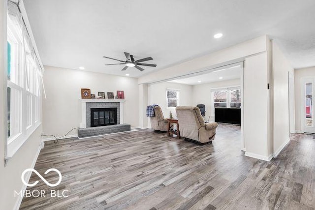 living area with a brick fireplace, wood finished floors, a ceiling fan, and recessed lighting