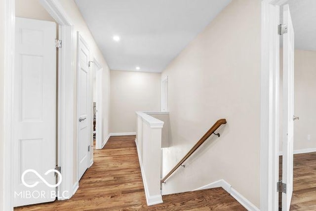 hall featuring recessed lighting, wood finished floors, an upstairs landing, and baseboards