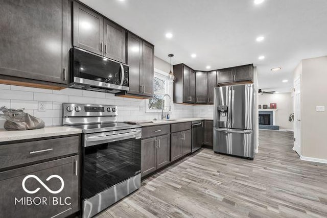 kitchen featuring light wood-style flooring, tasteful backsplash, a sink, and stainless steel appliances