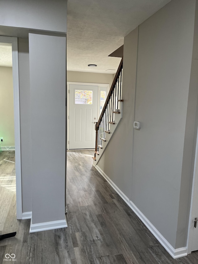 foyer entrance with wood finished floors, baseboards, and stairway