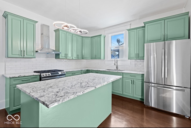 kitchen featuring wall chimney range hood, a kitchen island, sink, pendant lighting, and stainless steel appliances