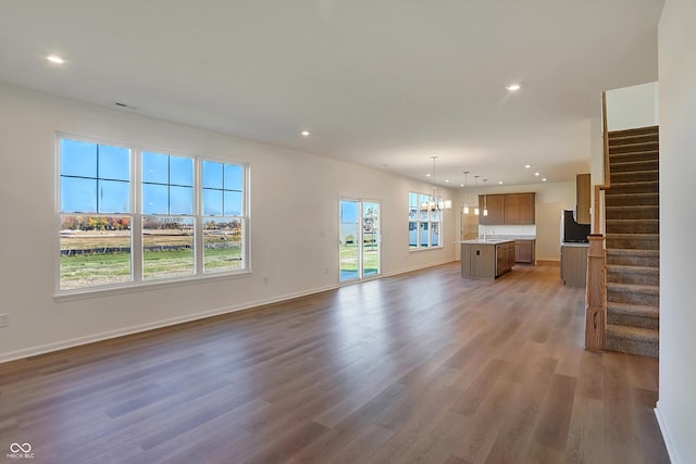 unfurnished living room with a wealth of natural light, sink, a chandelier, and dark hardwood / wood-style flooring