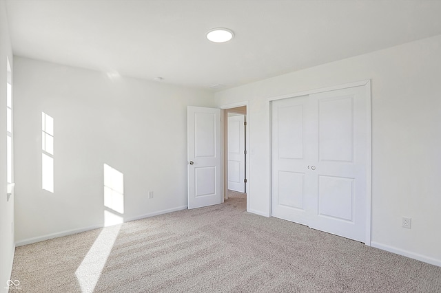 unfurnished bedroom featuring light carpet and a closet