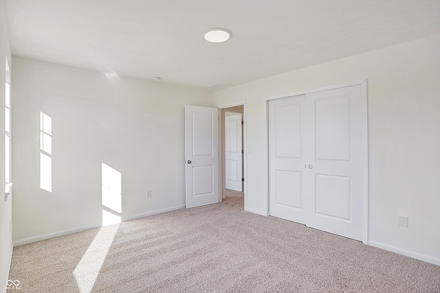 unfurnished bedroom featuring light colored carpet and a closet