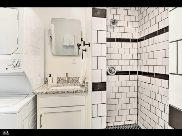 bathroom featuring vanity, stacked washer / dryer, and a tile shower