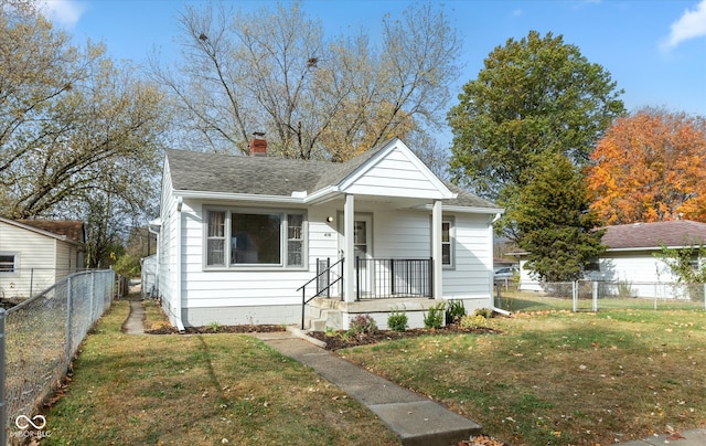 bungalow-style house with a shingled roof, a chimney, fence, and a front lawn