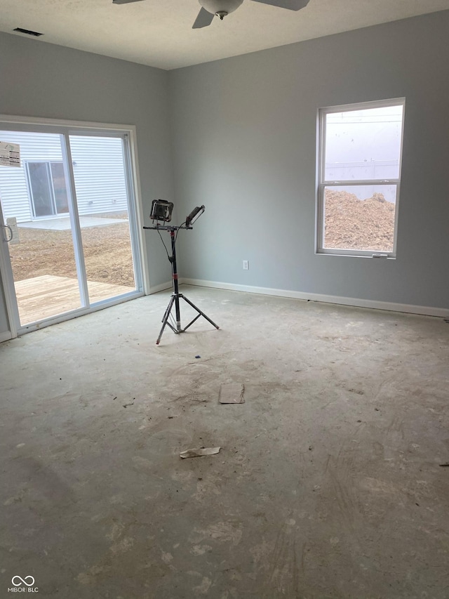 empty room featuring ceiling fan, plenty of natural light, and concrete floors