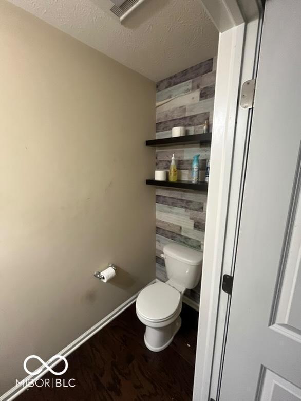 bathroom featuring toilet, wood-type flooring, and a textured ceiling