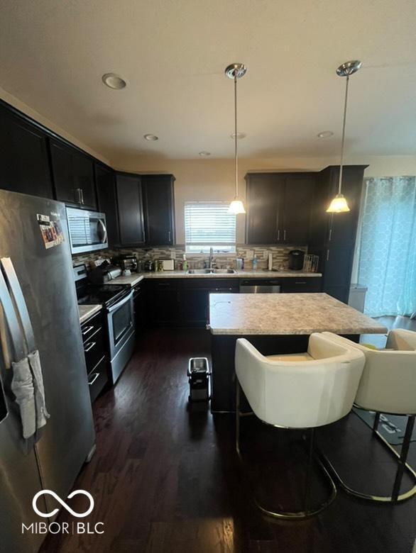 kitchen featuring a breakfast bar, pendant lighting, dark hardwood / wood-style flooring, and appliances with stainless steel finishes