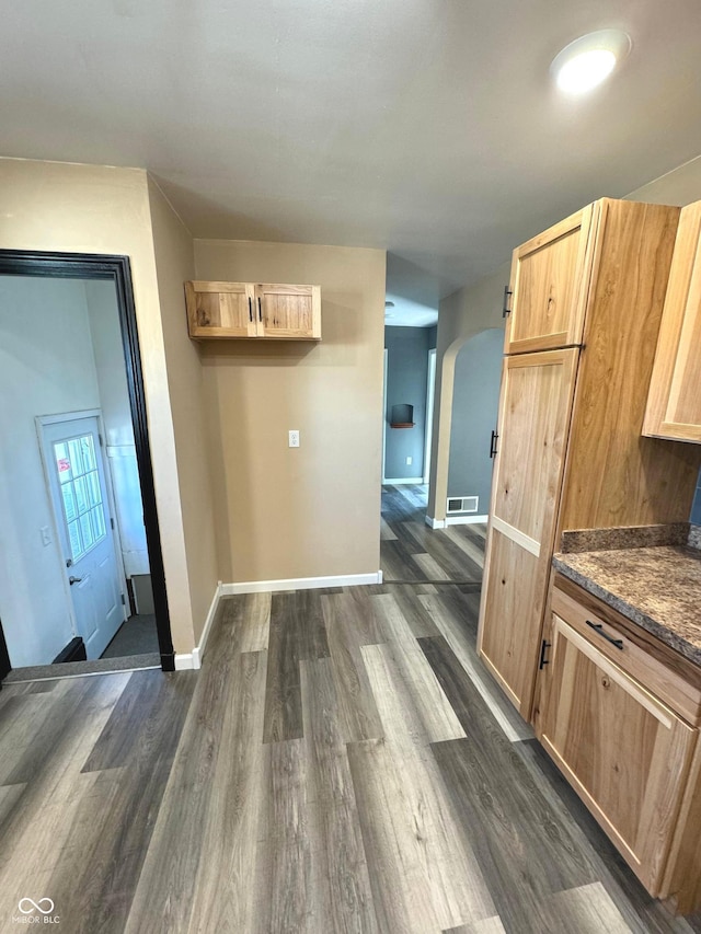 kitchen featuring light brown cabinetry, dark hardwood / wood-style flooring, and dark stone counters