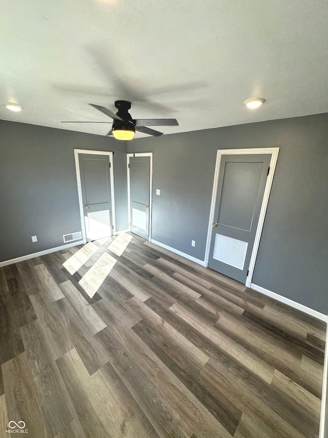 unfurnished bedroom featuring ceiling fan, dark hardwood / wood-style flooring, and a textured ceiling