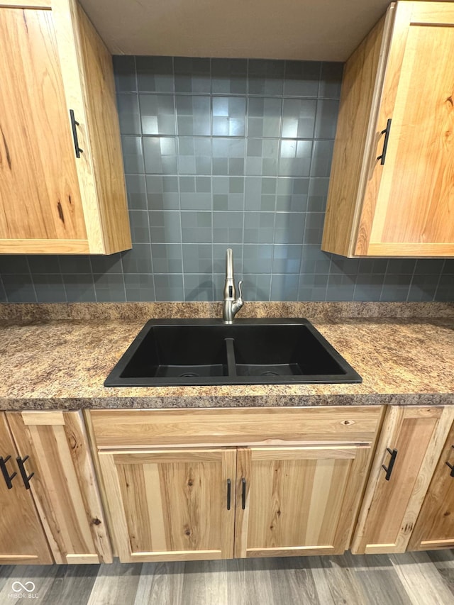 kitchen with decorative backsplash, dark hardwood / wood-style flooring, light stone counters, and sink