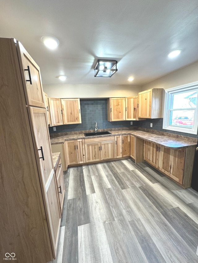 kitchen with decorative backsplash, light brown cabinets, light wood-type flooring, and sink