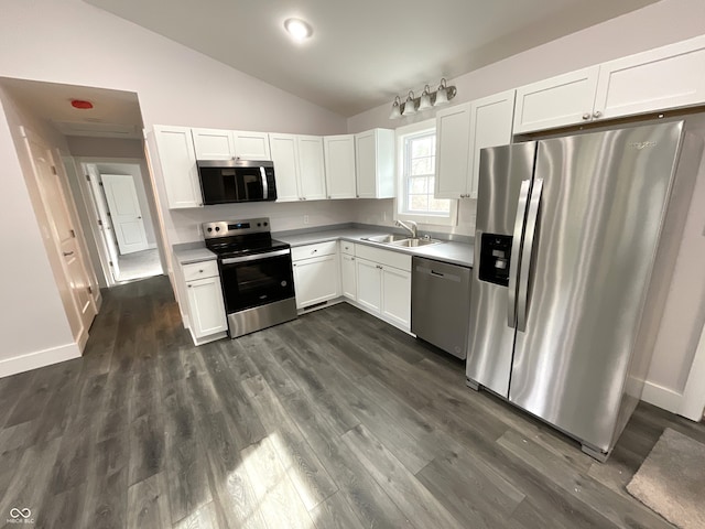 kitchen featuring sink, dark wood-type flooring, appliances with stainless steel finishes, white cabinetry, and vaulted ceiling