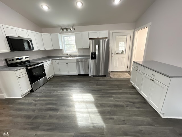 kitchen featuring appliances with stainless steel finishes, vaulted ceiling, sink, white cabinets, and dark hardwood / wood-style floors