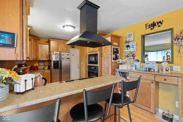 kitchen featuring island exhaust hood, light hardwood / wood-style flooring, a breakfast bar area, and black appliances