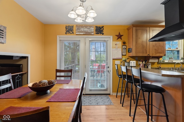 dining area with a chandelier, light hardwood / wood-style floors, a healthy amount of sunlight, and sink