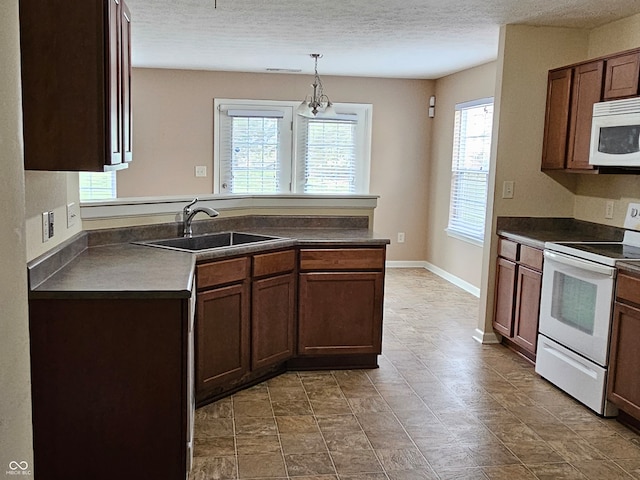 kitchen featuring a textured ceiling, white appliances, sink, an inviting chandelier, and hanging light fixtures