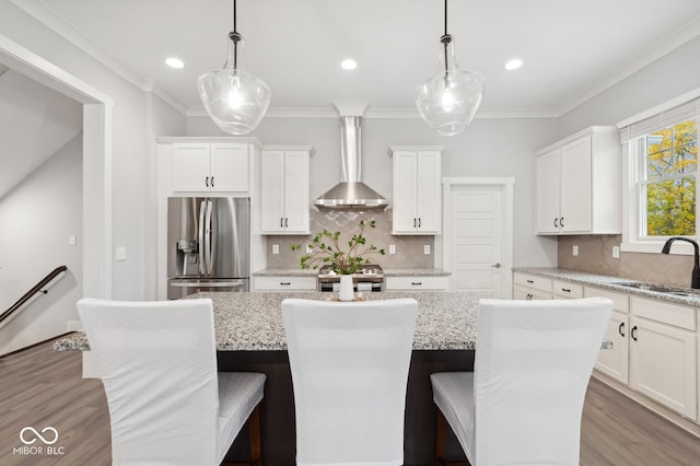 kitchen featuring pendant lighting, appliances with stainless steel finishes, wall chimney exhaust hood, and a center island