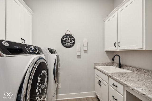 clothes washing area with cabinets, independent washer and dryer, sink, and hardwood / wood-style floors