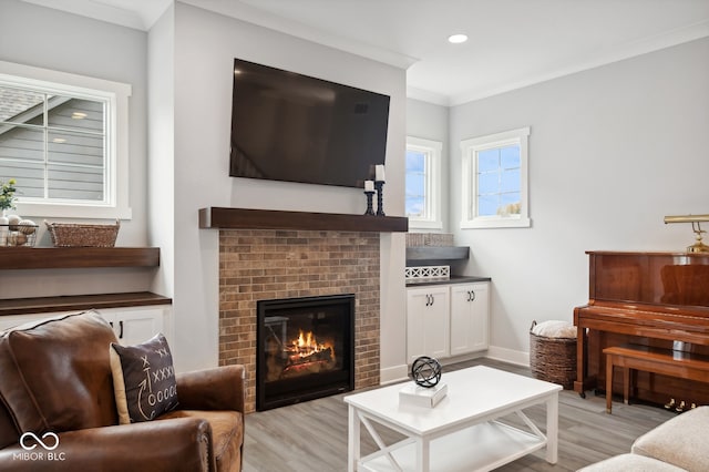 living room with a brick fireplace, light hardwood / wood-style floors, and crown molding