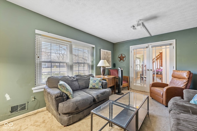 living room featuring a textured ceiling, light carpet, and french doors