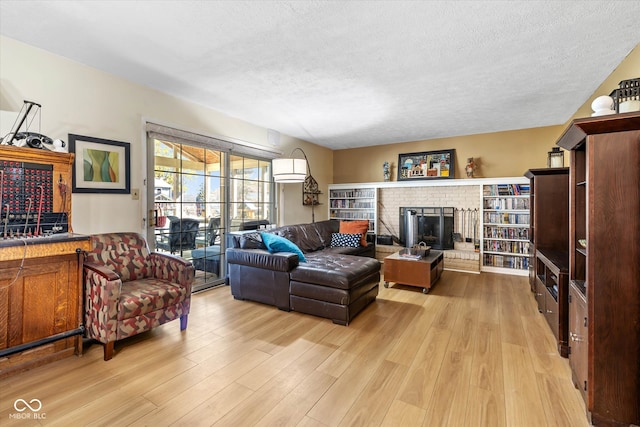 living room featuring a brick fireplace, light hardwood / wood-style flooring, and a textured ceiling