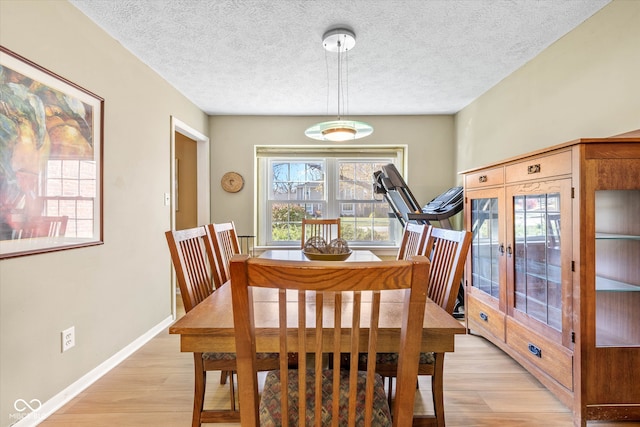 dining area with a textured ceiling and light hardwood / wood-style flooring