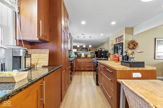 kitchen with wooden counters, light hardwood / wood-style floors, decorative light fixtures, and black range with electric stovetop