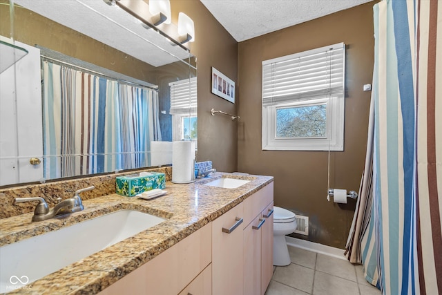 bathroom with a healthy amount of sunlight, tile patterned floors, a textured ceiling, and toilet