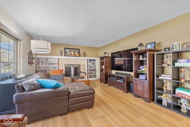 living room with light wood-type flooring, a textured ceiling, and a fireplace