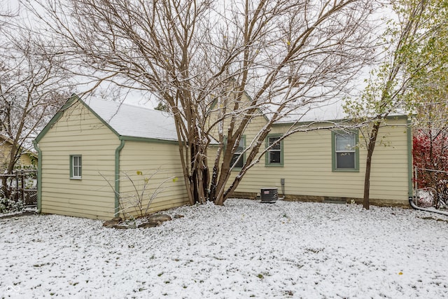 snow covered rear of property featuring central AC