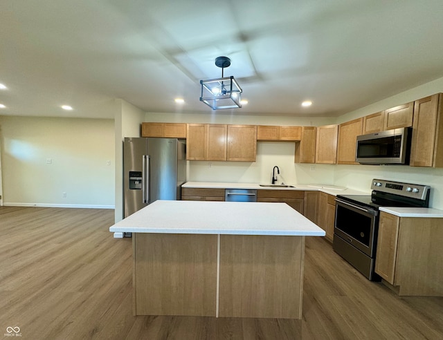 kitchen featuring stainless steel appliances, light wood-type flooring, pendant lighting, sink, and a center island