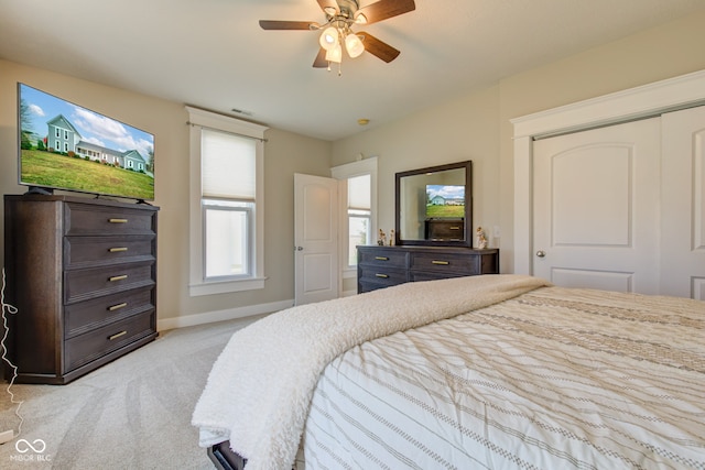 bedroom featuring light carpet, ceiling fan, and a closet