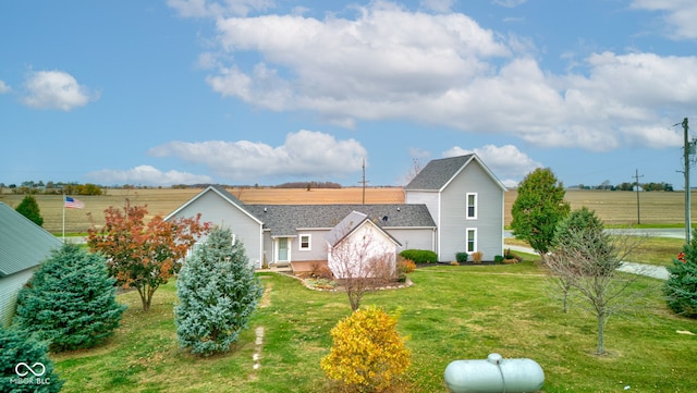 back of house with a rural view and a lawn