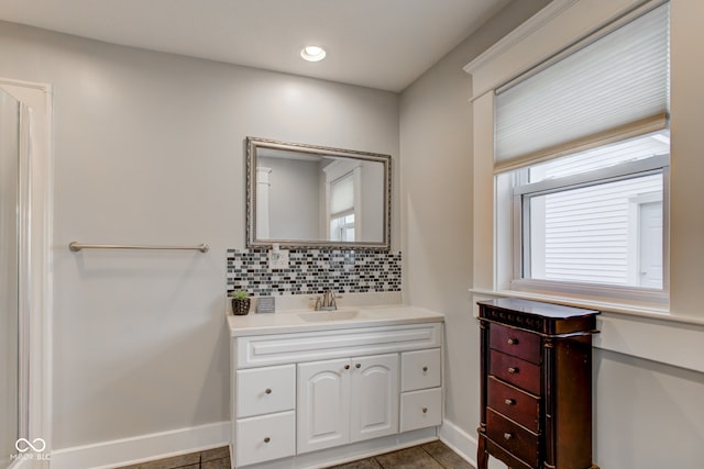 bathroom featuring decorative backsplash, tile patterned flooring, vanity, and a healthy amount of sunlight