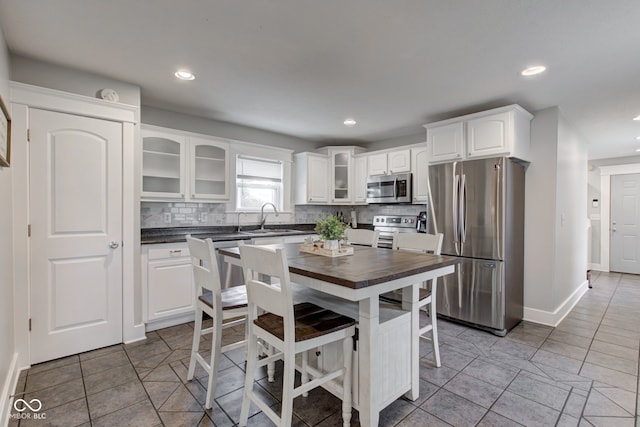 kitchen featuring tasteful backsplash, stainless steel appliances, light tile patterned floors, sink, and white cabinets