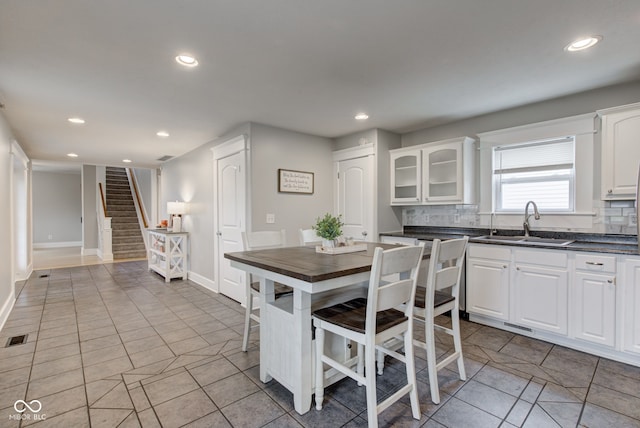 kitchen with white cabinetry, sink, tasteful backsplash, and light tile patterned flooring