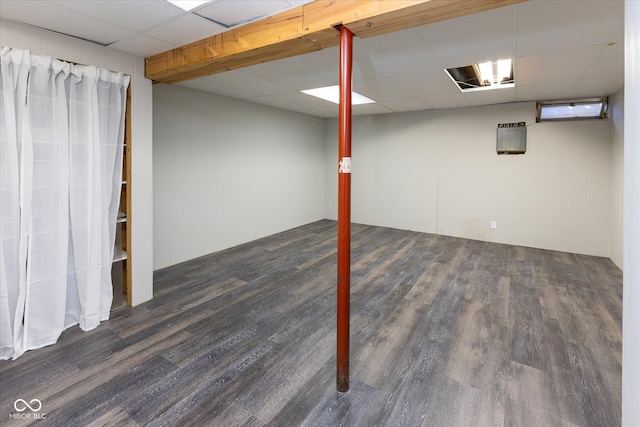 basement with a paneled ceiling and dark wood-type flooring