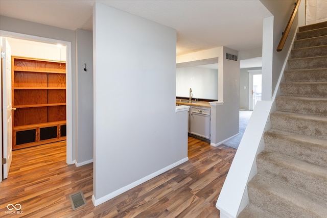 staircase featuring wood-type flooring and sink