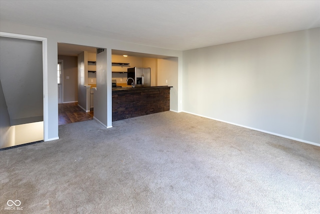 unfurnished living room with carpet floors and sink