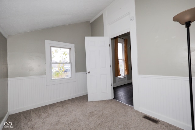 unfurnished bedroom with carpet floors and vaulted ceiling