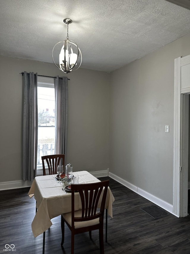 dining room featuring dark hardwood / wood-style floors, a textured ceiling, and a notable chandelier