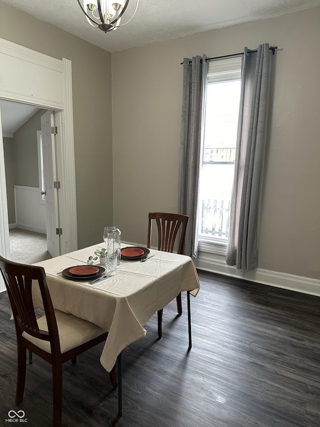 dining room featuring dark hardwood / wood-style flooring, a chandelier, and a textured ceiling