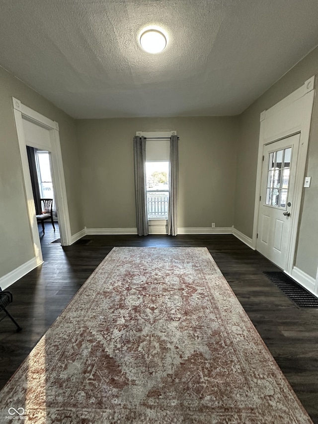 foyer with a healthy amount of sunlight, dark hardwood / wood-style flooring, and a textured ceiling