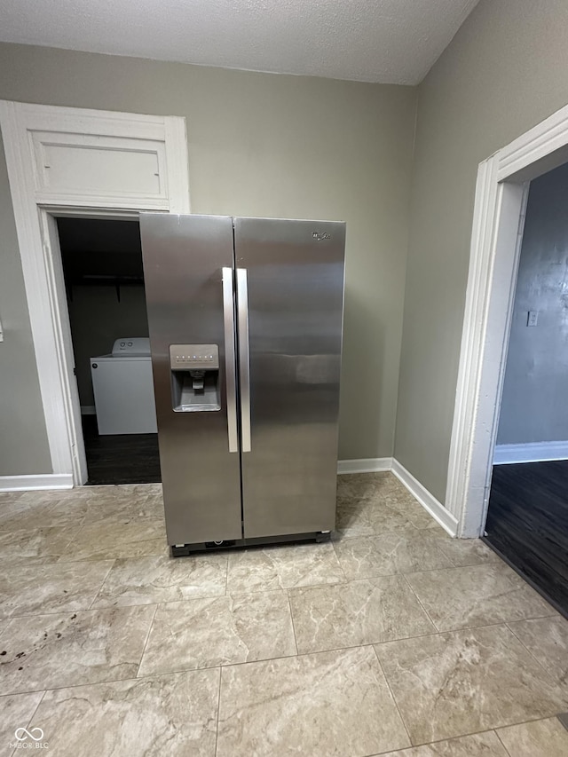 kitchen with stainless steel fridge, washer / dryer, and a textured ceiling